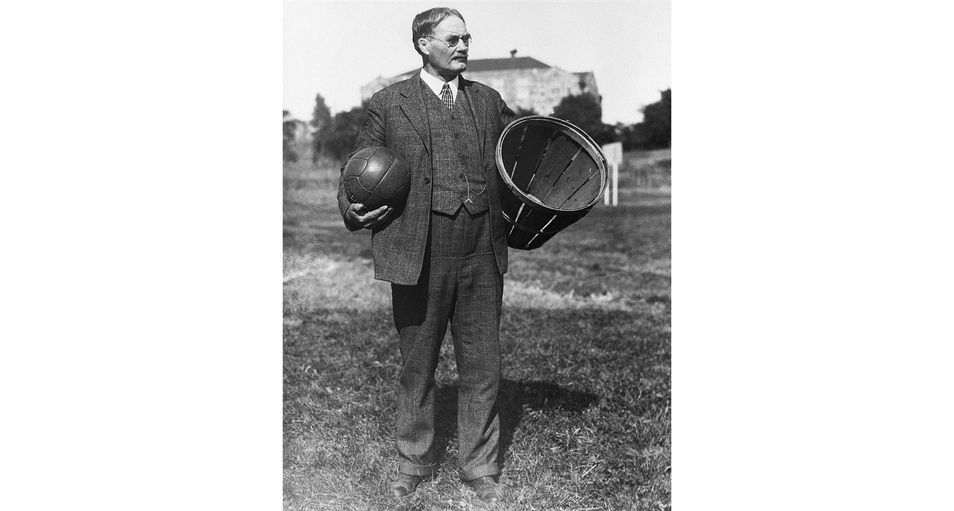 Dr. James Naismith with a basket and a specially designed ball. (Photo via Wikimedia Commons)