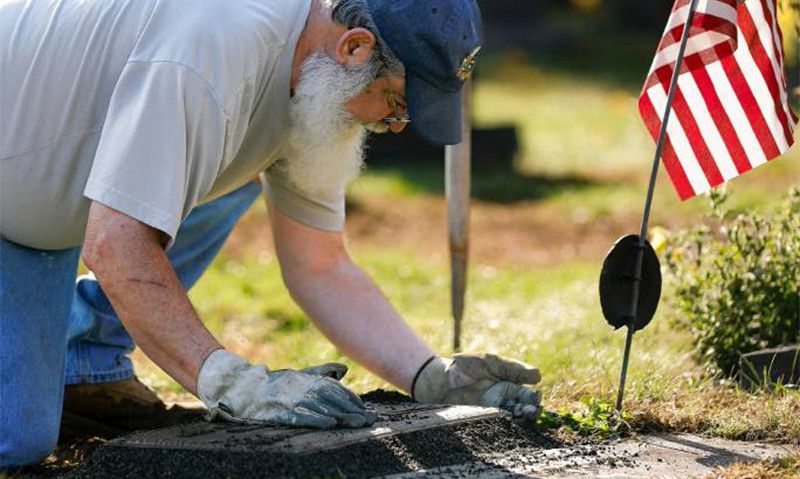 Legionnaire leading effort to clean up military memorial markers in local cemetery.